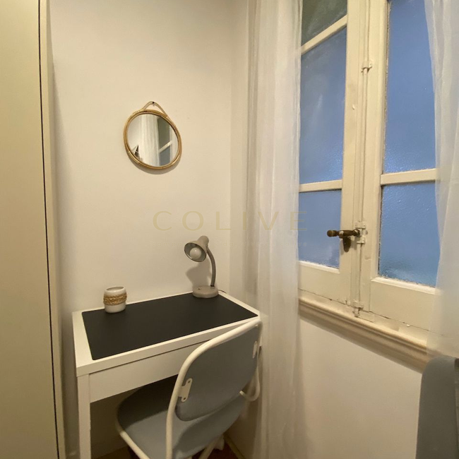 Escritorio con silla, armario y ventana hacia patio interior